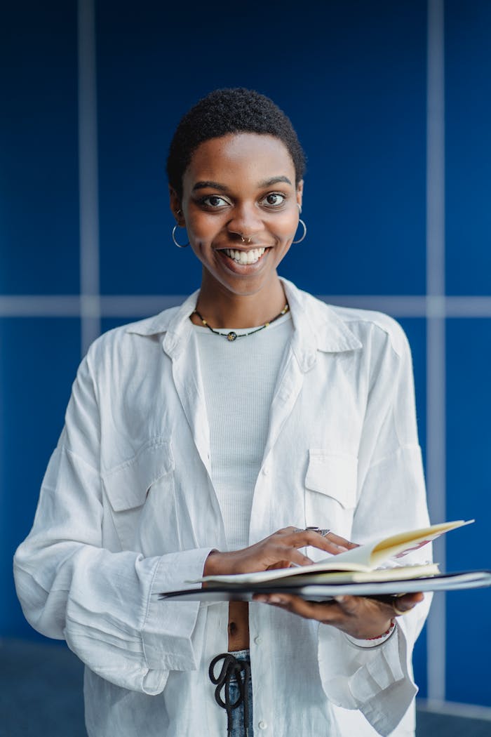 why-choose-us Smiling African American female student in casual clothes standing with notebooks on blue background and looking at camera